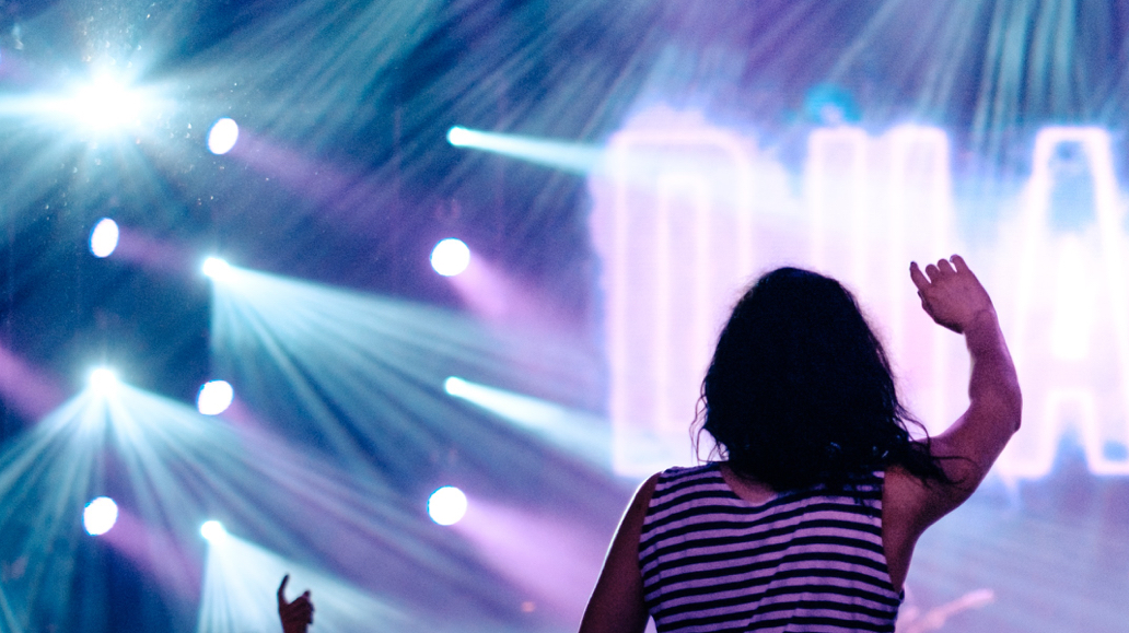 person cheering at concert with lights